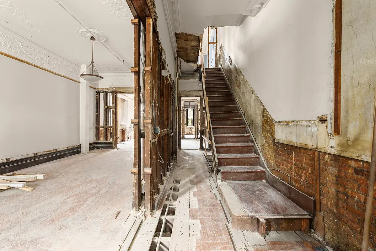 Parlor floor of 128 West 121st Street stripped to the studs, with the original staircase
