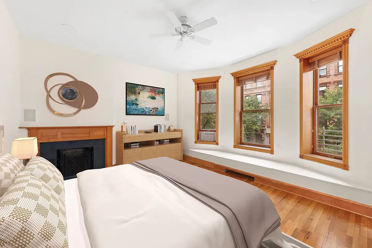 Virtually staged bedroom with fireplace and three windows at 14 West 121st Street