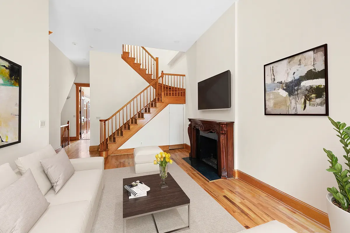Virtually staged living room with fireplace and staircase at 14 West 121st Street