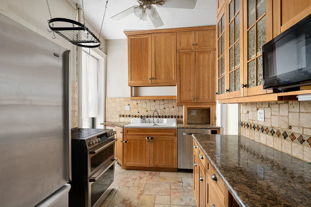 Kitchen with wood cabinets and granite counters at 523 West 121st Street #2