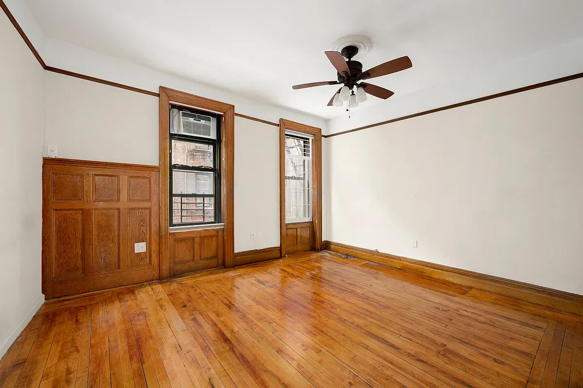 Empty living room with oak wainscoting at 523 West 121st Street #2