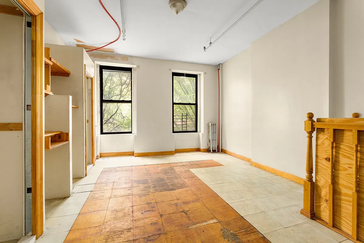 Unrenovated room with original staircase rail at 80 West 119th Street