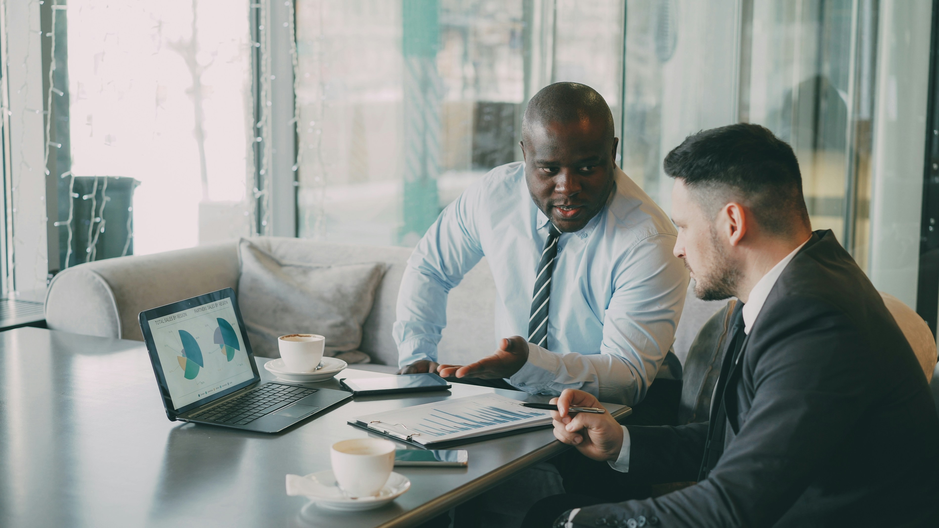 Real estate professionals reviewing NYC property data and market analytics on a laptop during a client meeting in a modern office